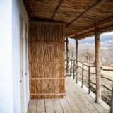 Pensiune rustică cu acoperiș de stuf pe malul unui canal, cu o barcă legată la ponton