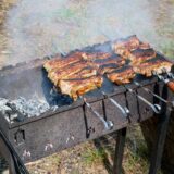 Bucăți de crap care se frig pe un grătar cu jar, pregătite pentru saramură pescărească